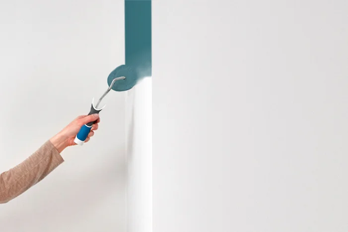 Hand streicht Wand mit Farbrolle